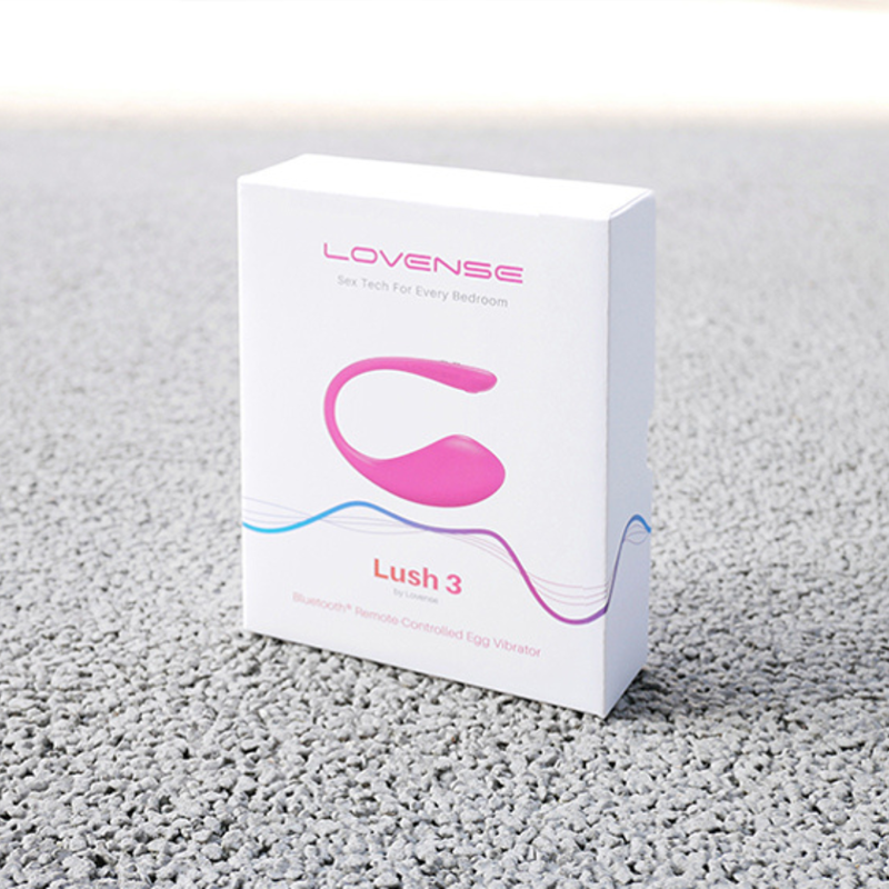 Lovense Lush 3 智能震蛋的白色商品包裝盒，立於灰色顆粒感背景上。